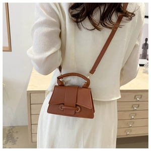 Brown lychee leather mini crossbody bag with top handle worn on a model's back