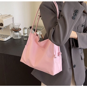 Detail of soft pink PU bucket bag with unique knot decoration on a stylish shoulder strap