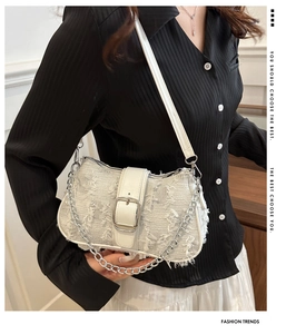Close-up of white tweed shoulder bag with belt buckle and silver chain details