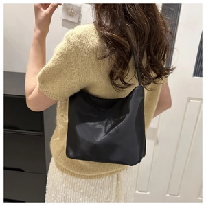 Detail of minimalist black nylon shoulder bag with embossed lettering on luxury fabric