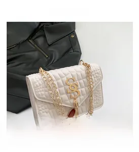 Détail du sac bandoulière crème avec motif pierre, logo SS doré et gland élégant