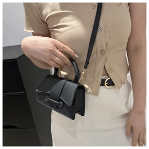 Detail of black lychee grain mini bag with gold hardware and detachable strap for women