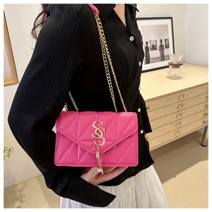Close-up of rose pink quilted crossbody bag featuring a gold logo and tassel detail