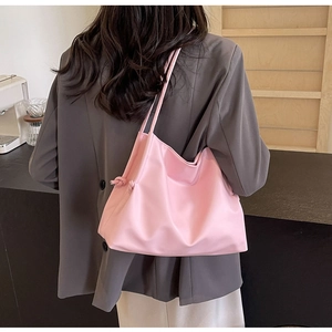Detail of light pink soft PU bucket bag with knot design worn with a grey blazer