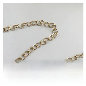 Détail de la bandoulière chaîne à bulles en métal doré sur un tissu texturé doux
