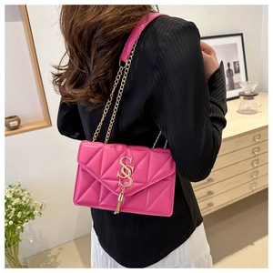 Detailed view of a fuchsia quilted crossbody bag with gold chain strap on a model