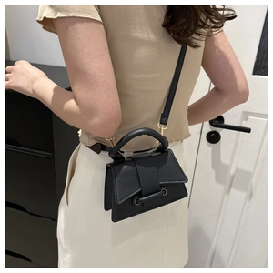 Mini black lychee leather top-handle bag with gold hardware shown on a model