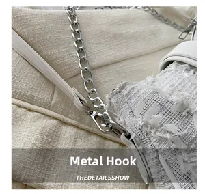 Detalle de ganchos metálicos plateados y cadena en bolso de tweed blanco suave