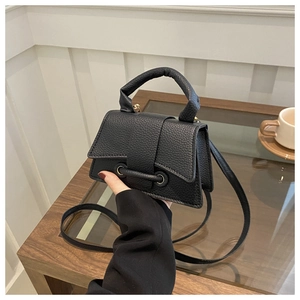 Close-up of black lychee grain leather saddle bag with unique circular hardware detail