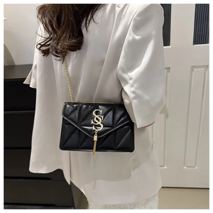 Detail of black quilted leather shoulder bag with gold metal logo and tassel pendant