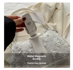 Detalle del cierre magnético en el bolso de mano blanco con textura de flecos