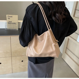 Detail of soft beige PU bucket bag with minimalist dual straps and side knot accents