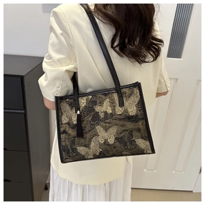 Detail of black silk tote bag with gold butterfly embroidery and tassel pendant decoration