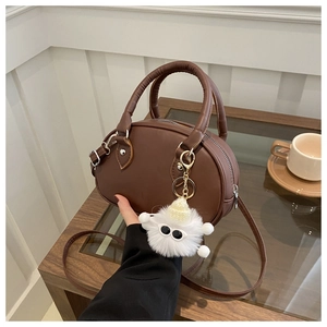 Sac bowling en cuir marron avec un pendentif peluche blanc mignon dans un cadre cosy