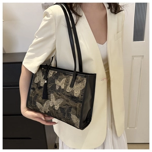 Detail of black silk tote bag featuring golden butterfly embroidery and silk tassel