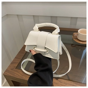 Detail of white lychee leather saddle bag with decorative strap and top handle