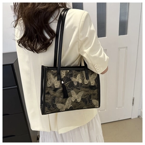 Macro shot of embroidered butterfly patterns and black tassel detail on tote bag