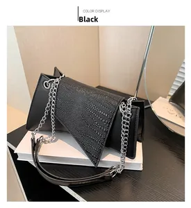 Detail of black crossbody bag with triangle flap, matte texture and silver chain strap