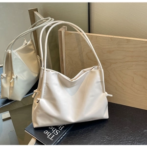 Minimalist cream soft PU bucket bag with side knot detail on a modern aesthetic background