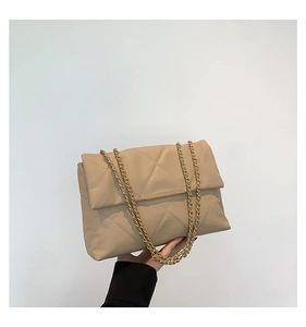 Detail of beige quilted shoulder bag featuring gold chain strap and metal trim decor