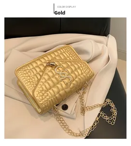 Détail de petit sac carré doré à motif crocodile avec chaîne métallique et logo