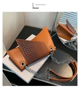 Detail of asymmetrical brown crossbody bag with crocodile embossed texture and chain strap