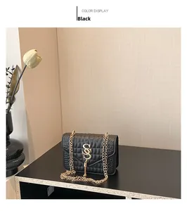 Détail d'un sac matelassé noir en similicuir avec logo doré et pompon décoratif