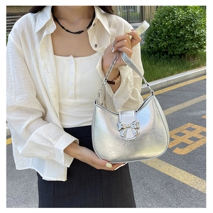 Close-up of metallic silver bag showing ruched leather texture and bow metal buckle