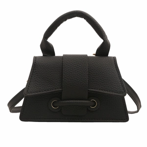 Minimalist black lychee leather mini handbag with round handle and gold ring buckle