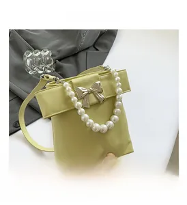 Close-up of sweet bow decoration and elegant pearl handle on a green crossbody bag