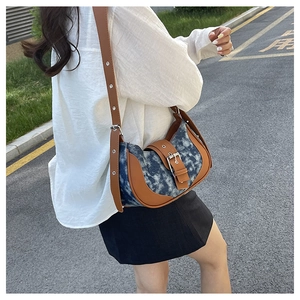 Detail of blue denim contrast saddle bag with brown leather trim and silver metal buckle