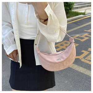 Detail of pink hobo bag with white embroidered patterns and silver logo plate accent