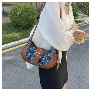 Detail view of crescent underarm bag with blue cloud texture and large metal buckle
