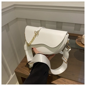 Détail du sac selle blanc montrant la chaîne dorée et la large bandoulière textile