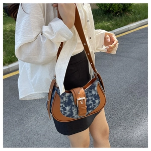 Outdoor shot of a vintage denim saddle bag with brown leather trim and metal buckle