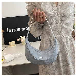 Close-up of light blue hobo bag with white embroidery stitching and metal logo