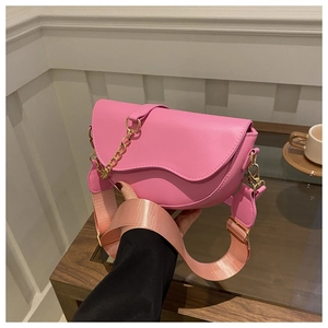 Détail du sac selle rose avec chaîne dorée et large bandoulière en tissu réglable