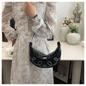 Close-up of black crescent bag with heart embroidery and stylish white stitching detail