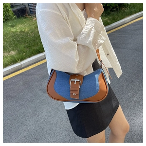Detail of blue denim and brown leather patchwork shoulder bag with buckle strap