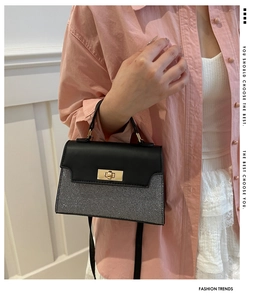 Close-up of stylish contrast color bag with gold buckle lock held by a model