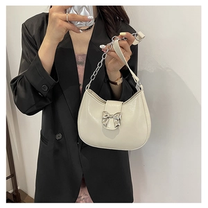 Cream white saddle shoulder bag with silver bow accent and metal chain strap