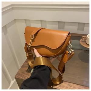 Détail du sac selle marron avec rabat ondulé, chaîne dorée et large bandoulière