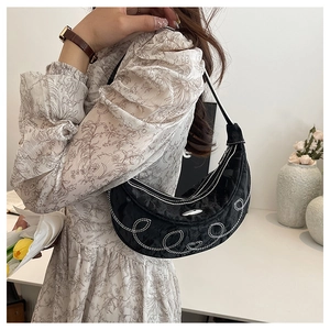 Detail of black crescent hobo bag featuring white circle embroidery and ruched texture
