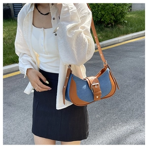 Detail of blue denim and brown leather contrast stitching on a vintage saddle bag
