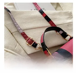 Detail of golden metal buckle and pink plaid strap on stylish square crossbody bag