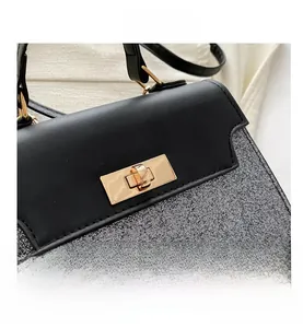 Detail of the golden metal buckle on black leather and silver sequin handbag