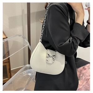 Close-up of creamy white crescent shoulder bag with silver bow detail and chain strap