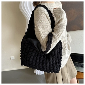 Close-up of black popcorn textured bubble tote bag on a model in a minimal setting
