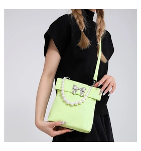 Close-up of lime green crossbody bag featuring a silver bow and large pearl handle