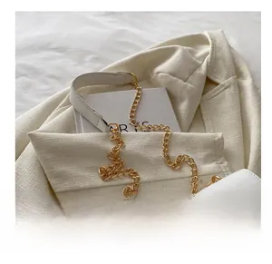 Detail of white leather shoulder bag with golden CC clasp and metal chain strap
